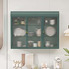 a green cabinet sitting above a counter next to a potted plant and other kitchen utensils