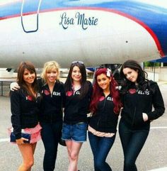 four girls standing in front of an airplane