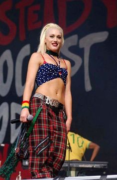 a woman standing on top of a stage wearing plaid pants and a cropped top