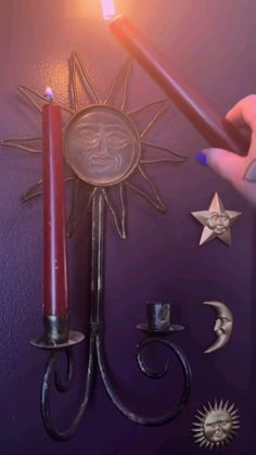 a person holding a lit candle next to a wall decoration with stars and moon on it