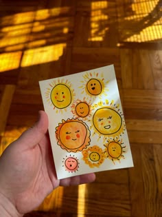 a hand holding up a card with sun and moon faces on it in front of a wooden floor