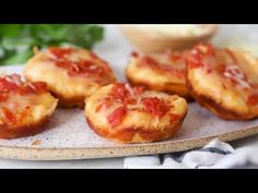 mini pizzas with cheese and tomato sauce on a plate next to some parsley