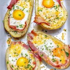 four eggs and bacon on top of potato skins in a white baking dish with parmesan sprinkles