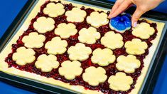 someone is decorating some cookies with blue icing on a cookie sheet in the shape of hearts