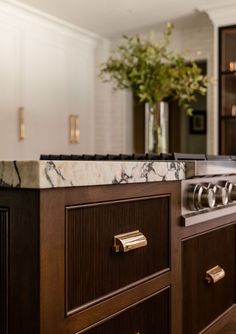 a kitchen with marble counter tops and wooden cabinets in the background is a vase full of flowers