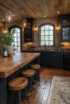 a large kitchen with wooden floors and black cabinetry, along with stools that match the hardwood flooring