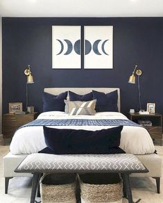 a bedroom with blue walls, white bedding and two framed pictures on the wall