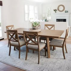 a dining room table with six chairs and a rug on the floor in front of it