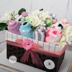 a basket filled with stuffed animals sitting on top of a white table next to flowers