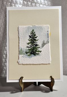 a painting of a pine tree is displayed on a white tablecloth with two antlers