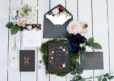 the wedding stationery is laid out with flowers and greenery