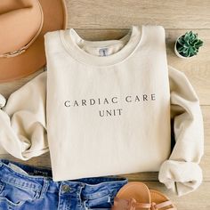 a white sweatshirt with the words cardigan care unit on it next to denim shorts and sandals