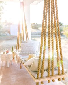 a porch swing made out of rope with pillows on it and some other items in the background