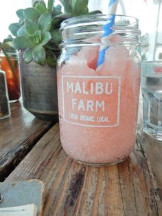 a mason jar filled with pink liquid sitting on top of a wooden table next to a potted plant