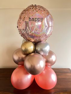 a bunch of balloons sitting on top of a table with a happy birthday balloon in the middle