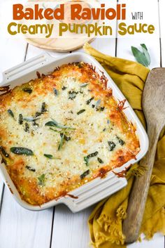 baked ravioli with creamy pumpkin sauce in a casserole dish next to a wooden spoon