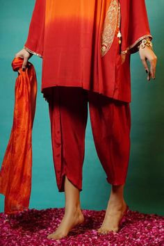 Coral and burnt red natural crepe hand tie dyed kurta with all over abstract pattern, side pockets, dori and mirror placement embroidery. Paired with pleated cowl draped dhoti pant and pure silk ombre dyed stole.
Components: 3
Pattern: Tie Dye and Embroidered
Type Of Work: Abstract Pattern, Dori, Mirror and Handmade Tassels Work
Neckline: V Neck
Sleeve Type: Bell Sleeves
Fabric: Natural Crepe, Stole: Crushed Pure Silk Dye
Color: Coral,Red
Other Details: 
Tasselled stole edges
Approx. product wei Mirror Placement, Placement Embroidery, Dhoti Pants, Burnt Red, Hand Tie, Coral Red, Color Coral, Silk Dyeing, Pant Set