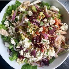 a salad in a white bowl with lettuce and cranberries