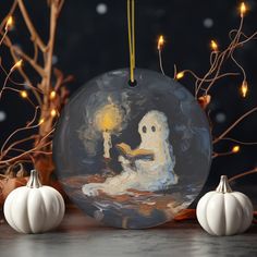 a glass ornament with a painting of a ghost holding a candle in it