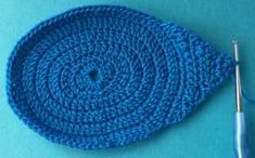 a crocheted blue dishcloth with a needle next to it on a blue surface