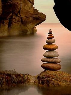 a stack of rocks sitting on top of a beach next to a body of water