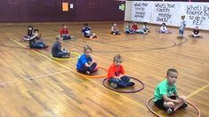 several children sitting on the floor with toys in front of them, while one child is holding a hoop