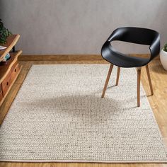 a black chair sitting on top of a wooden floor next to a white area rug