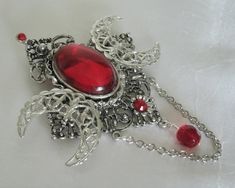 Triple Moon Brooch This beautiful silver plated brooch has silver plated crescent moons, a red setting, rhinestones, metal chain, seed beads and red faceted glass bead. Can also be worn as a cloak pin. It is 2.75 inches wide and 3.75 inches long with bead drop and chain. Cloak Pin, Wicca Jewelry, Moon Brooch, New Plymouth, Goddess Jewelry, Wiccan Jewelry, Pagan Jewelry, Triple Moon, Faceted Glass