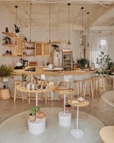 an open kitchen and dining area with stools, tables, and potted plants