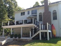 a large white house with a surfboard on the front lawn and stairs leading up to it