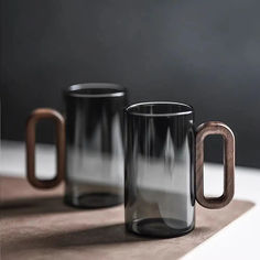 two black and brown coffee mugs sitting on top of a table next to each other