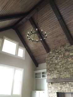 a living room with a stone fireplace and wooden ceiling