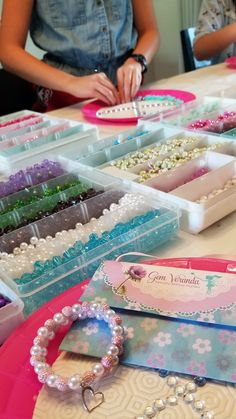 a table topped with lots of trays filled with different types of beads and bracelets