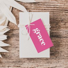 a pink price tag sitting on top of a piece of paper next to white flowers