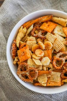 a white bowl filled with cheetos and nuts on top of a gray cloth