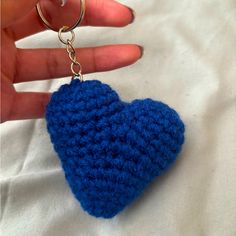 a blue crocheted heart keychain being held by someone's hand