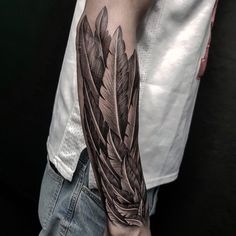 a man's arm with a feather tattoo on the left forearm and right arm