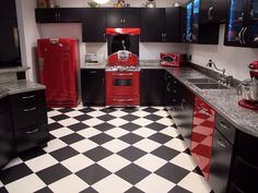 a black and white checkered floor in a kitchen with red appliances on the counters