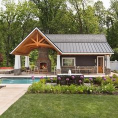 a backyard with a swimming pool and covered patio area next to a large stone fire place