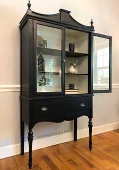 a black china cabinet sitting on top of a hard wood floor