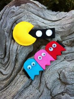 three different colored hair clips sitting on top of a piece of drifty wood with googly eyes