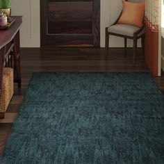 a living room with a blue rug on the floor next to a chair and table