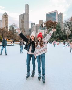 two young women standing on an ice rink with their arms in the air