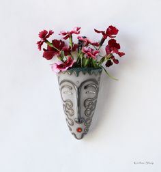 a vase filled with red flowers on top of a white wall