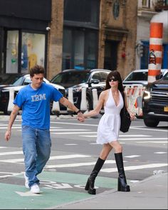 a man and woman crossing the street holding hands