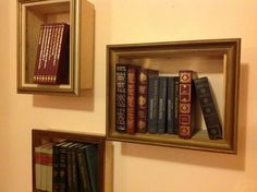 three framed books are sitting on the wall next to each other, and one is empty