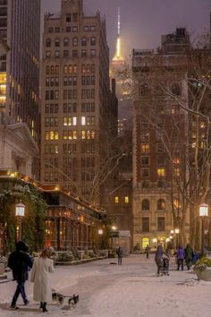 people are walking in the snow near tall buildings