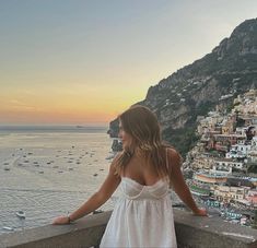 a woman standing on top of a balcony next to the ocean