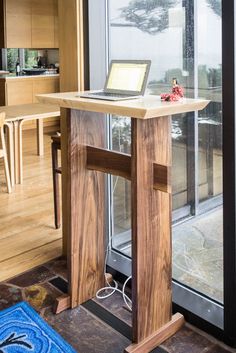 a laptop computer sitting on top of a wooden desk next to a glass door in a living room