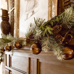 a mantel decorated with pine cones and ornaments